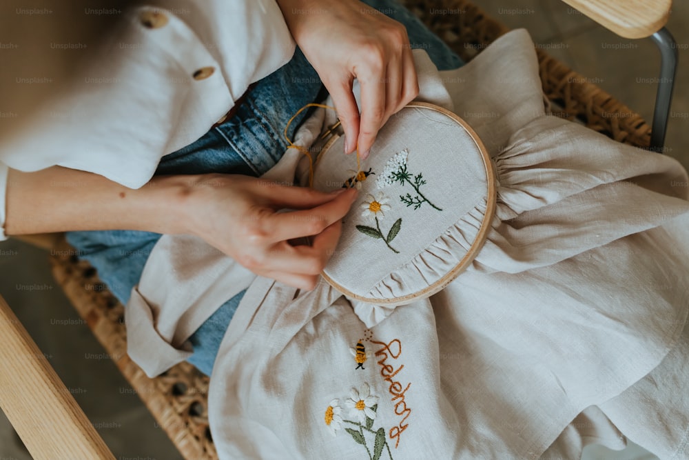 a woman is stitching a flower on a pillow