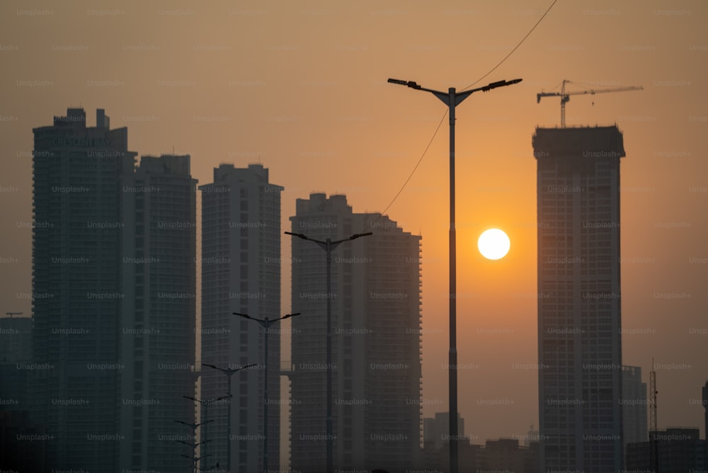 the sun is setting over a city with tall buildings