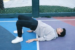 a person laying on a tennis court with a tennis racket
