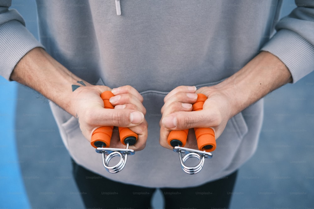a man holding two orange grips in his hands