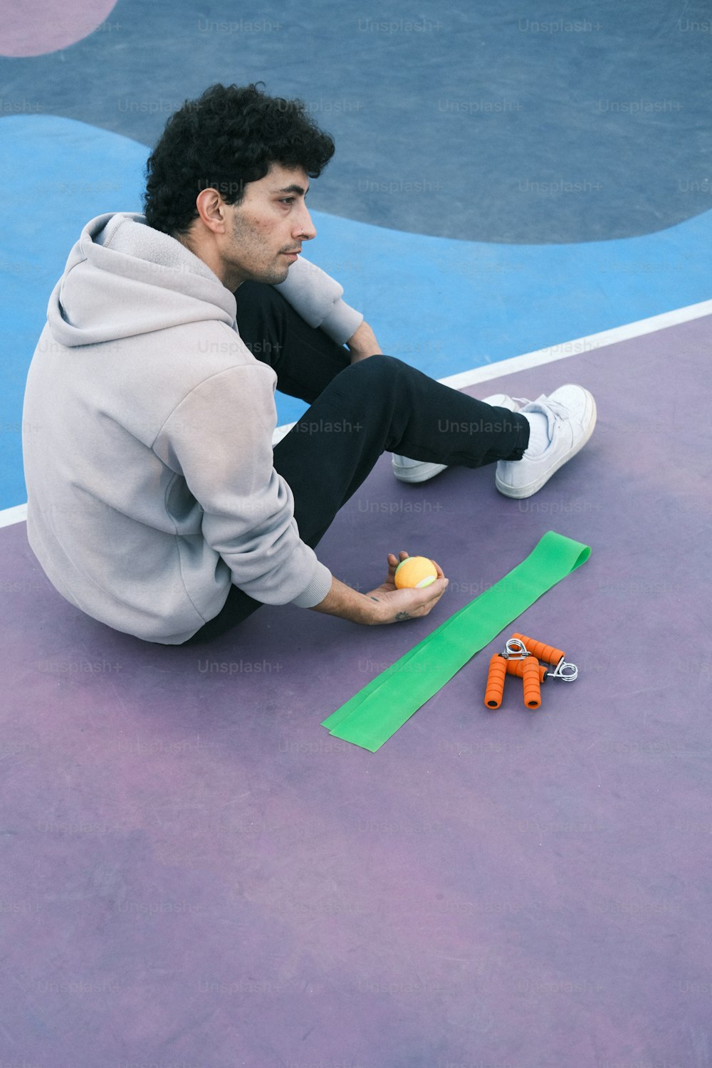 a man sitting on a tennis court holding a tennis ball