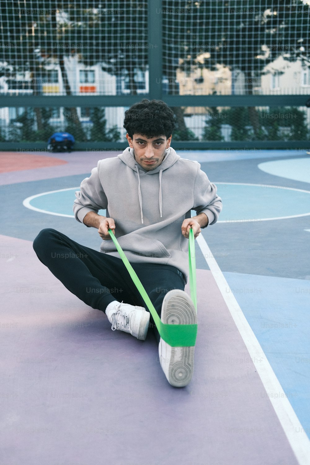 a man sitting on a basketball court holding a green handle