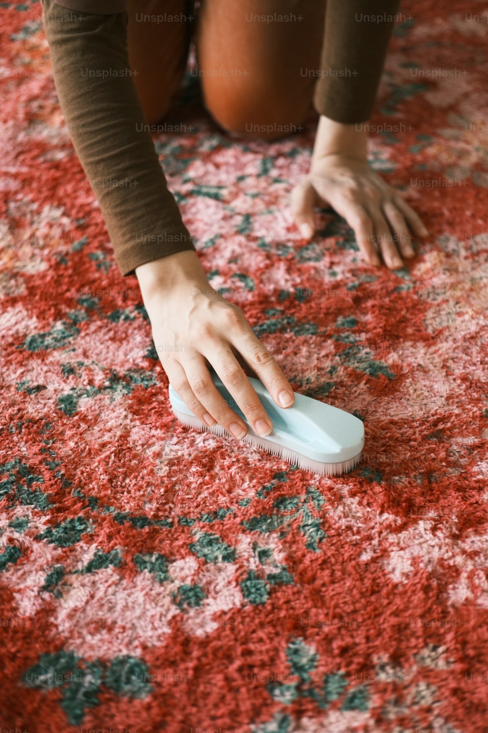 une personne agenouillée sur un tapis avec une brosse à la main