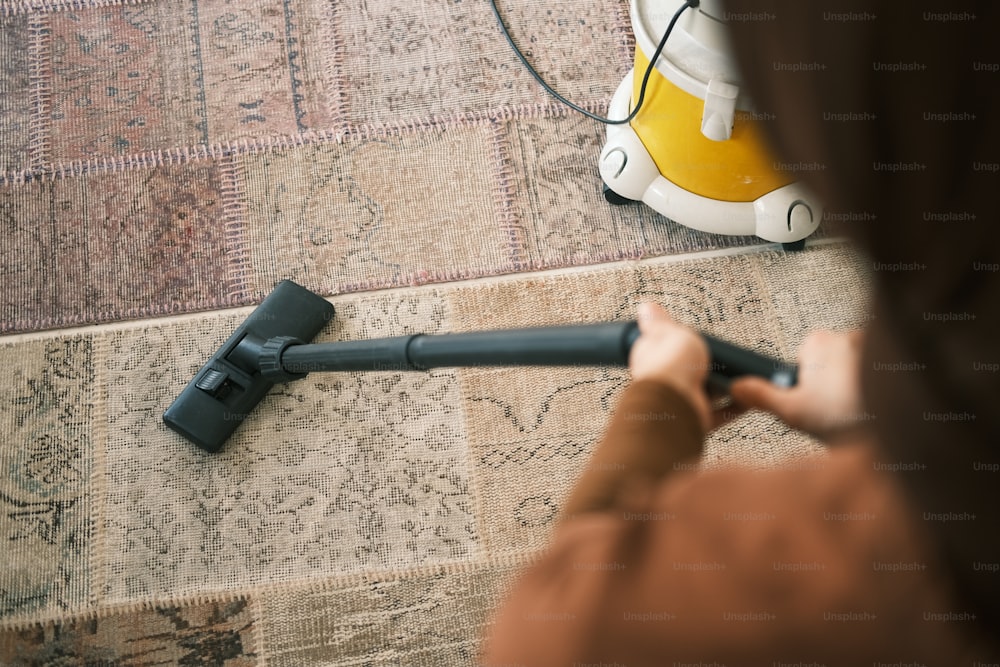 una persona che usa un aspirapolvere per pulire un tappeto
