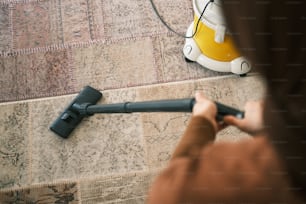 Una persona que usa una aspiradora para limpiar una alfombra