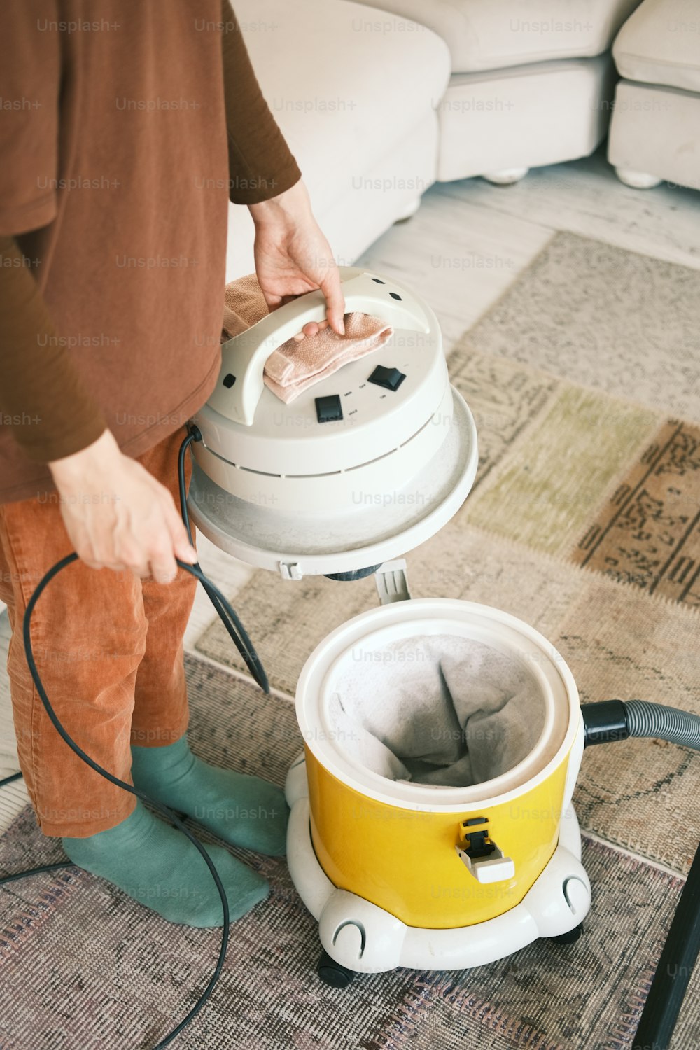 Una persona que usa una aspiradora para limpiar una alfombra