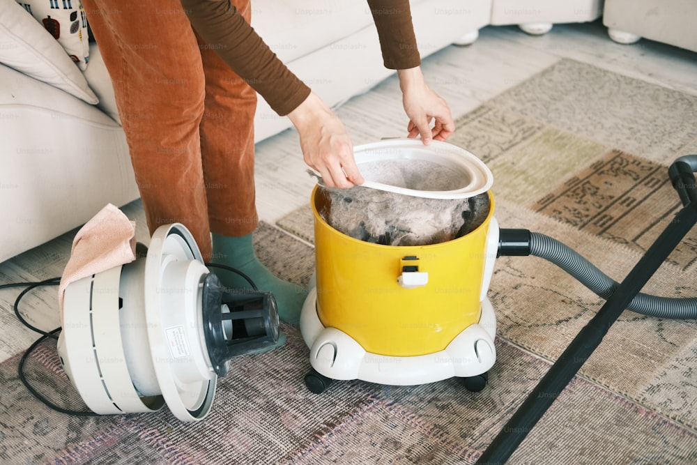 une personne utilisant un aspirateur pour nettoyer un tapis