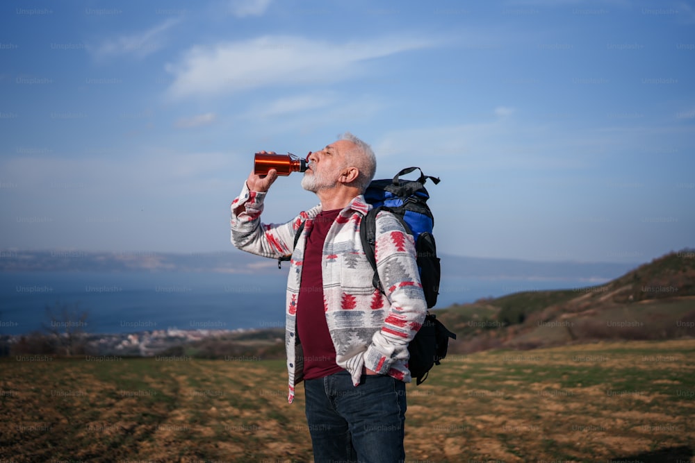 a man with a backpack drinking from a bottle