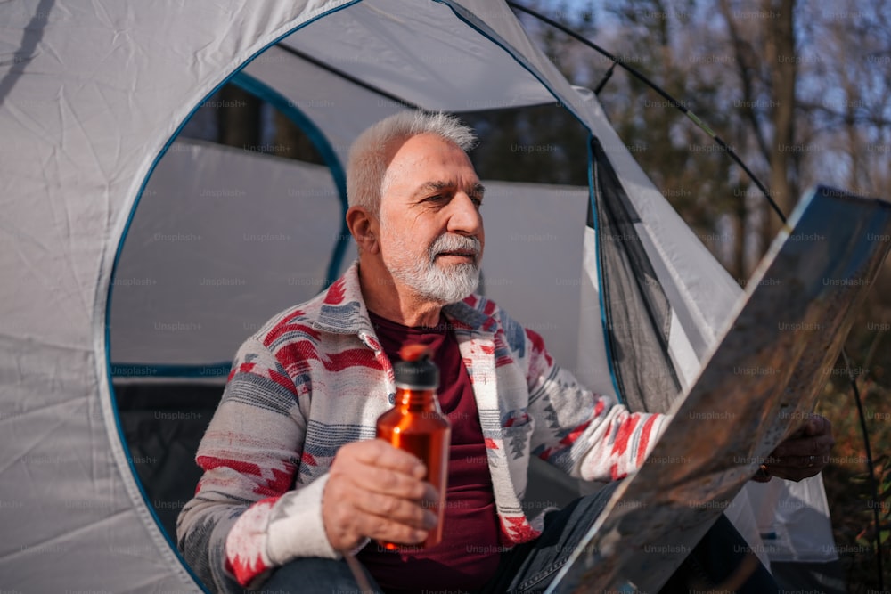 a man sitting in a tent holding a beer