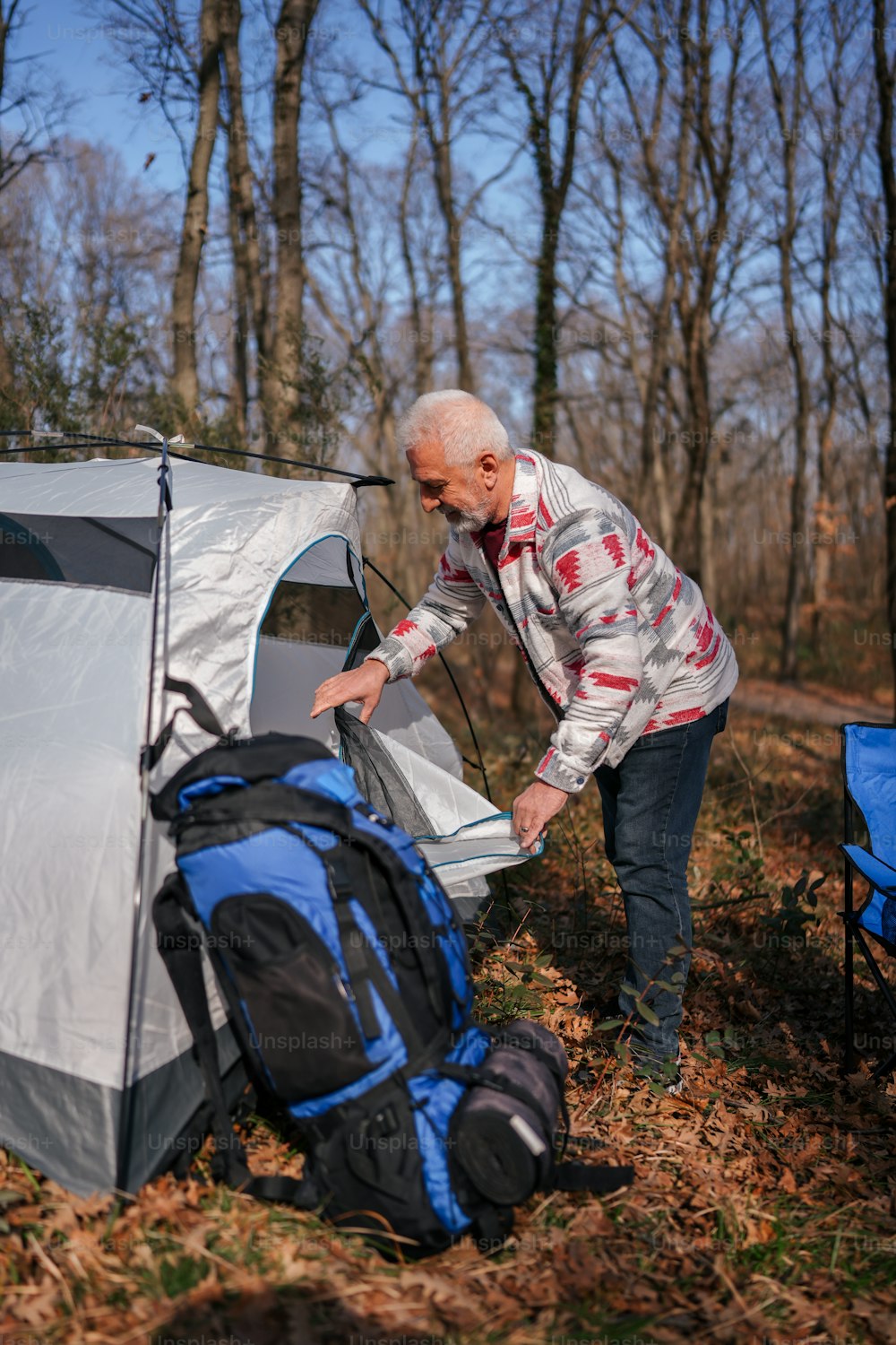 a man putting a tent in the woods