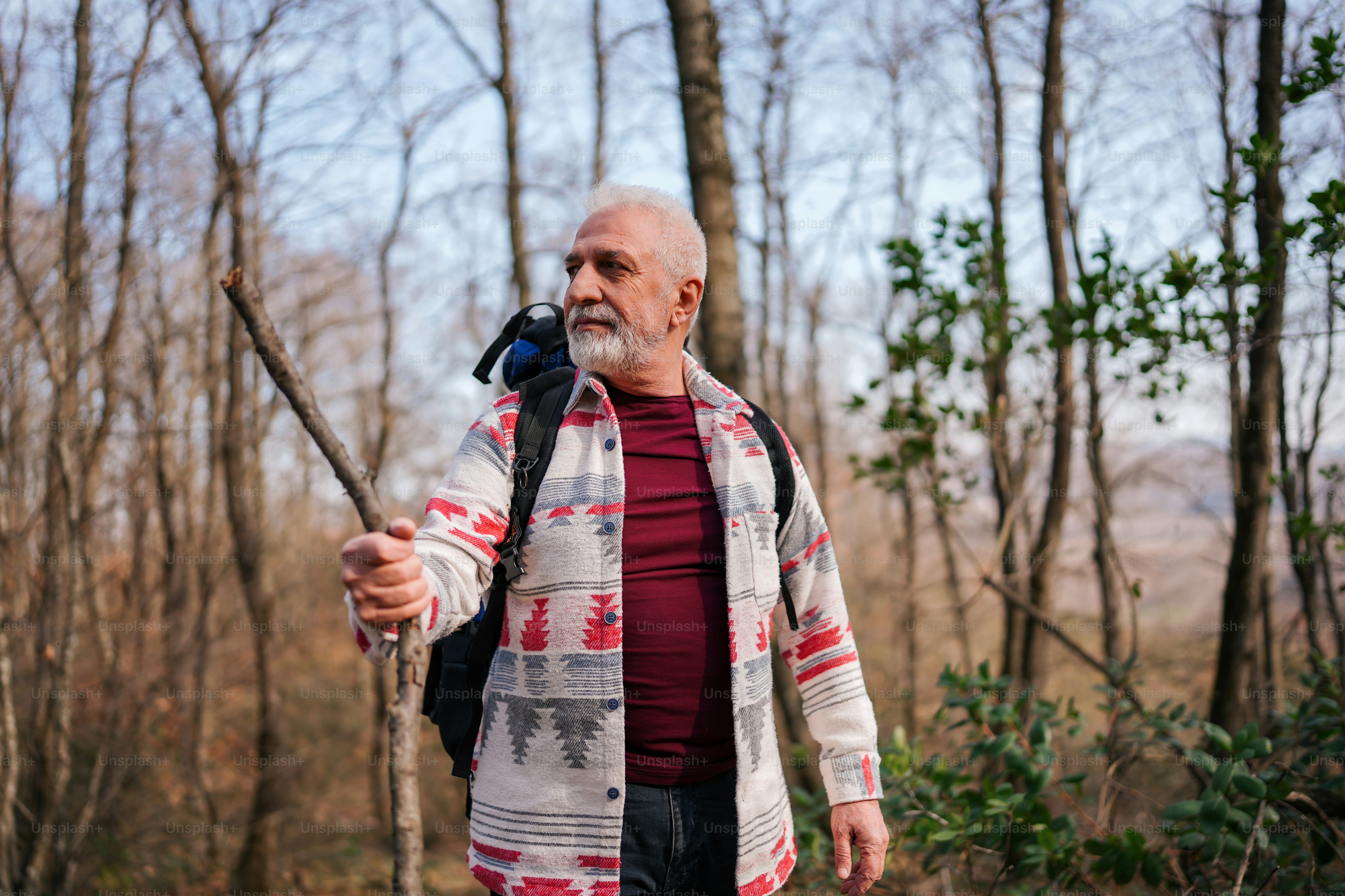 um homem segurando uma vara em uma área arborizada