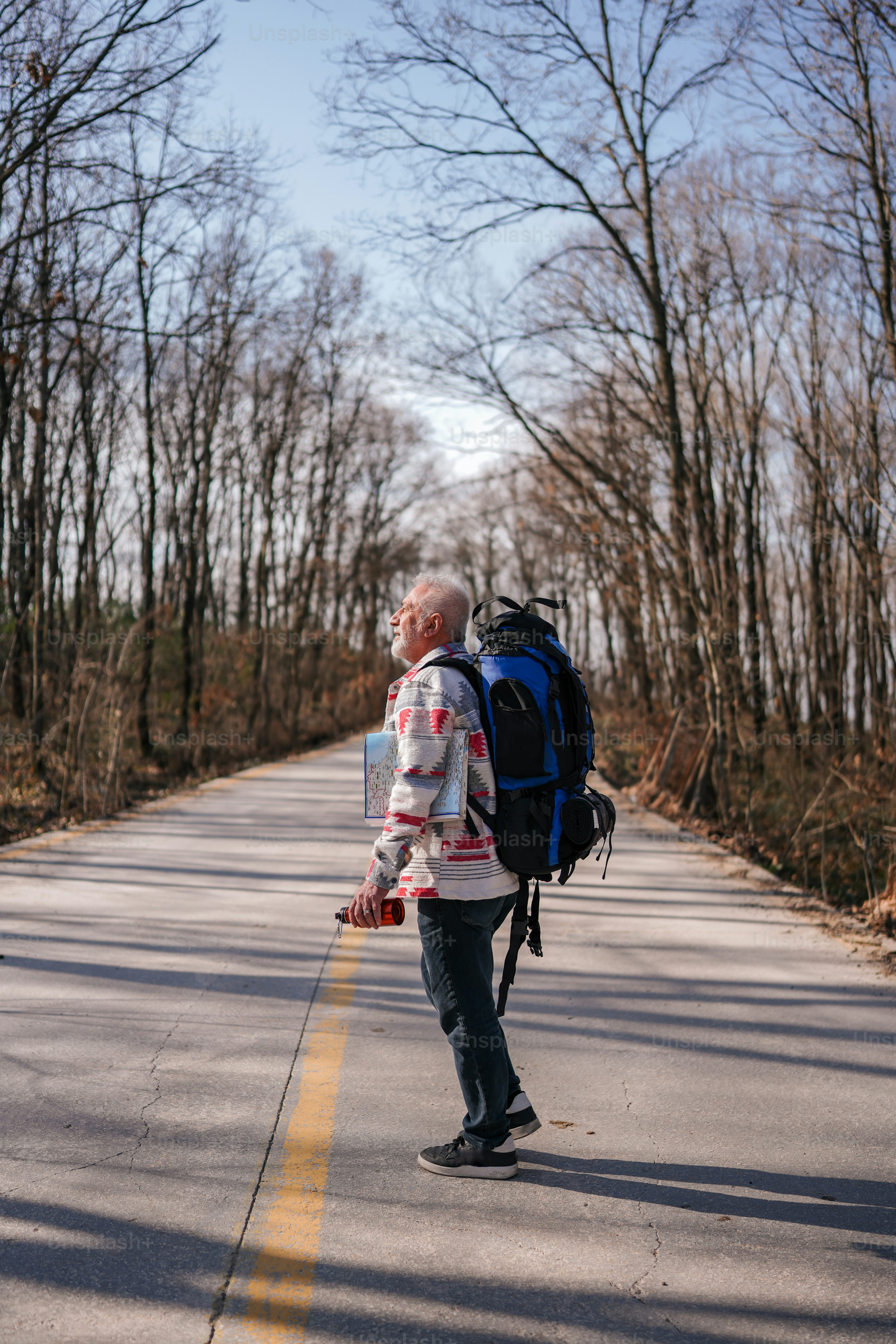 A man walking down a road with a backpack on his back photo – Travel ...