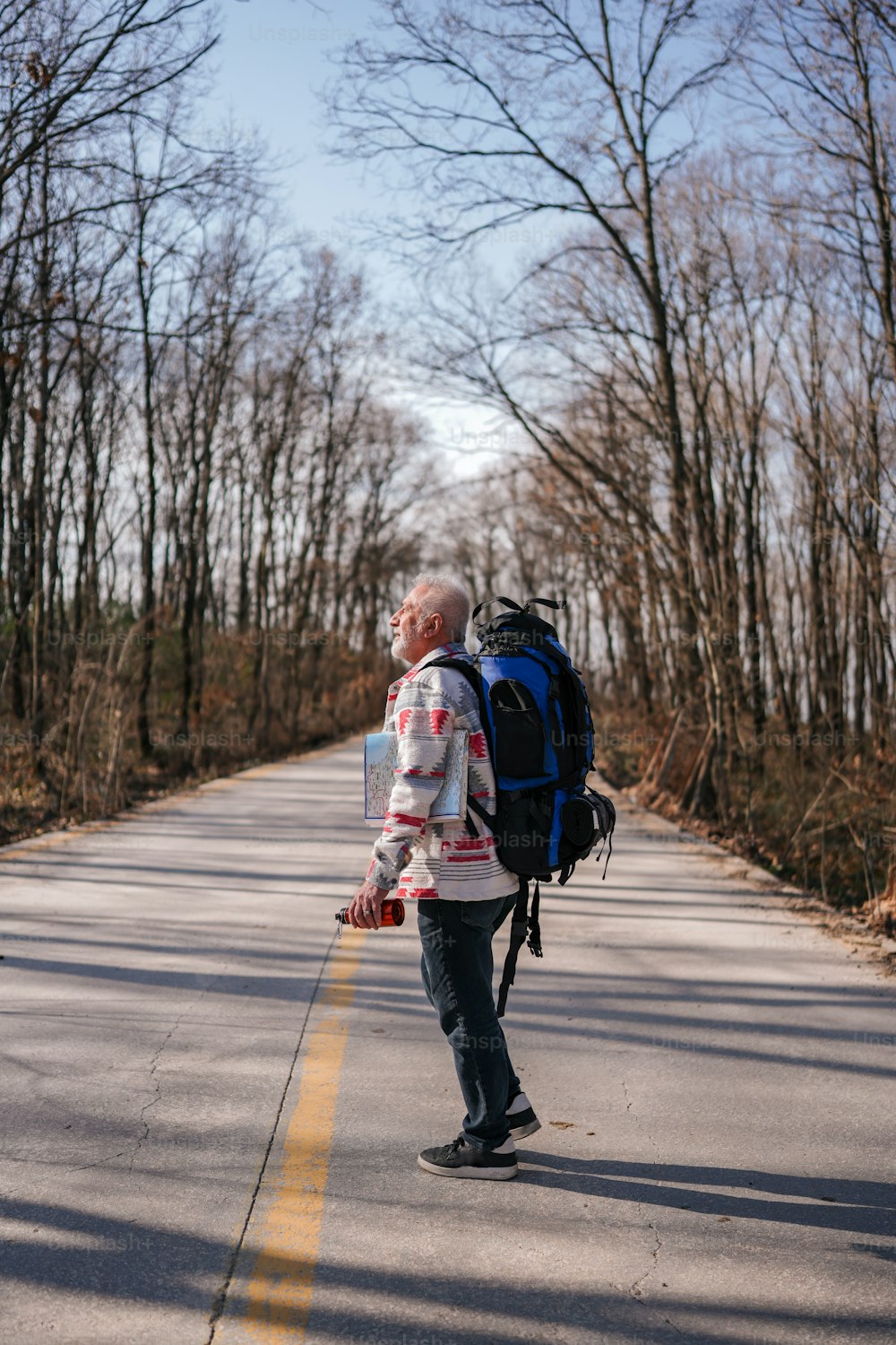 a man walking down a road with a backpack on his back