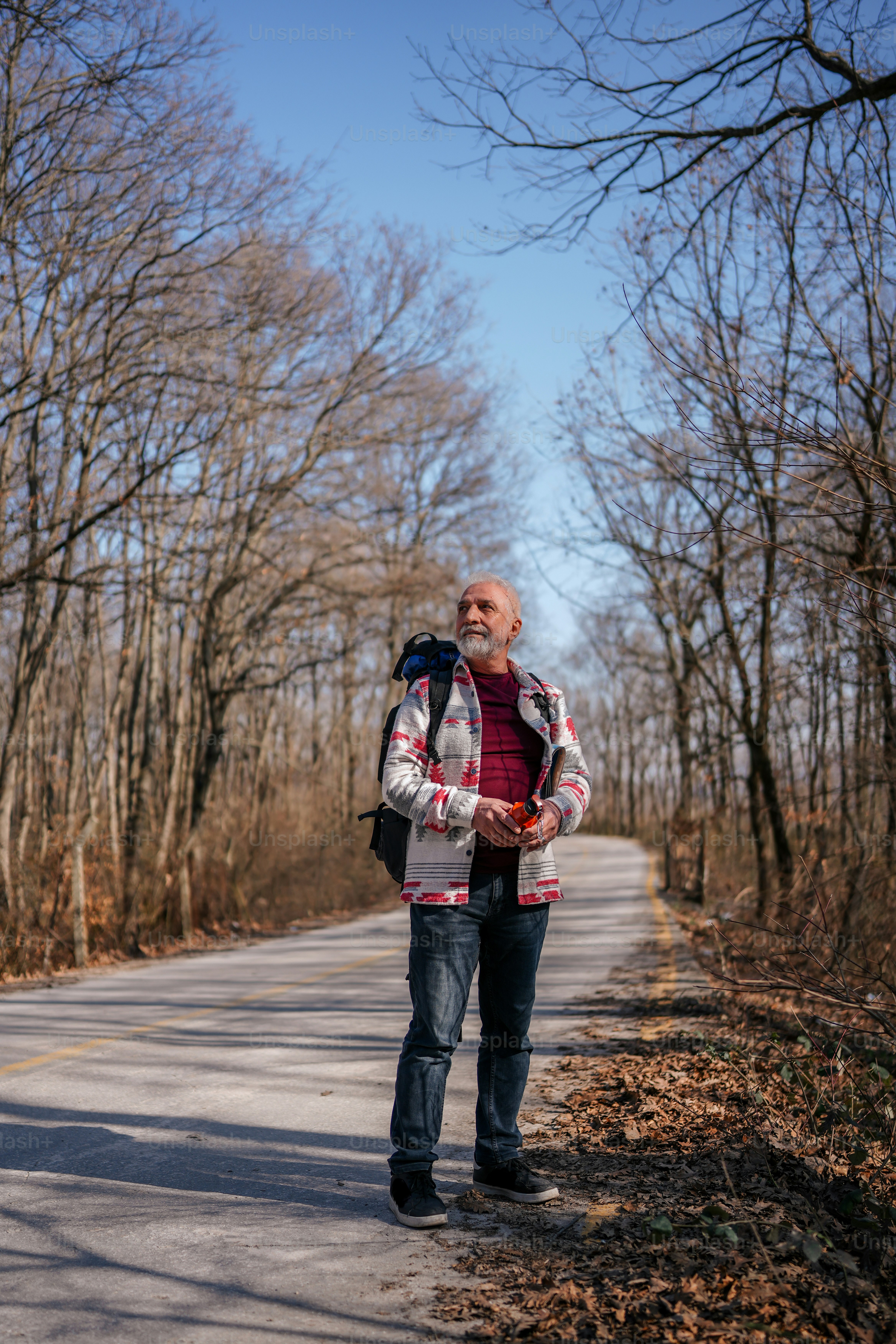 um homem de pé ao lado de uma estrada ao lado de uma floresta