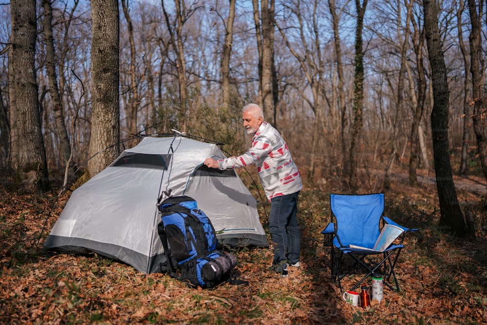 a man standing next to a tent in the woods