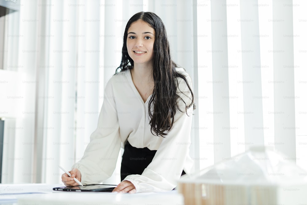 Eine Frau im weißen Hemd sitzt am Schreibtisch