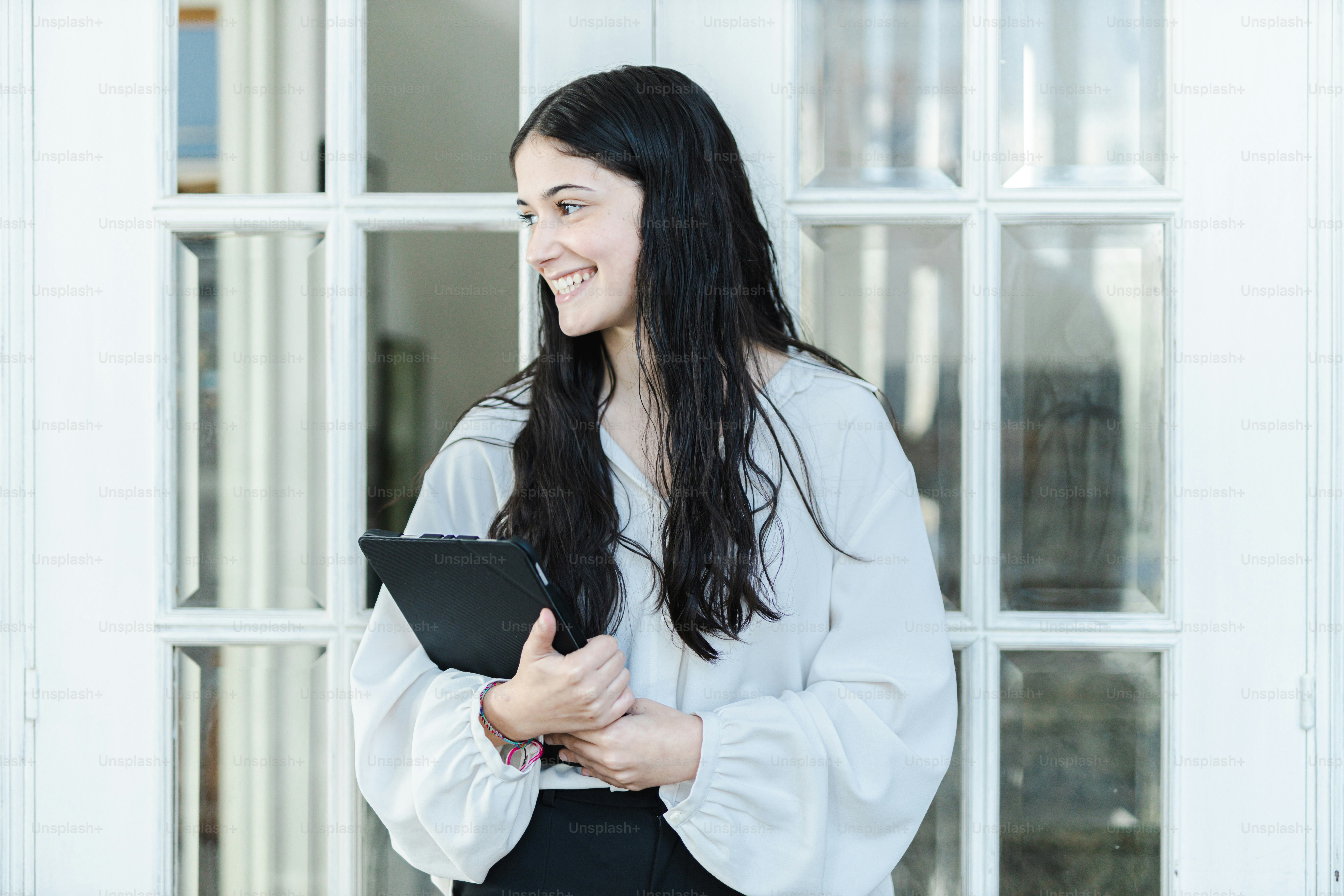 Une femme debout devant une fenêtre tenant une tablette