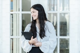 a woman standing in front of a window holding a tablet