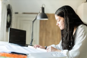 a woman sitting at a desk working on a laptop