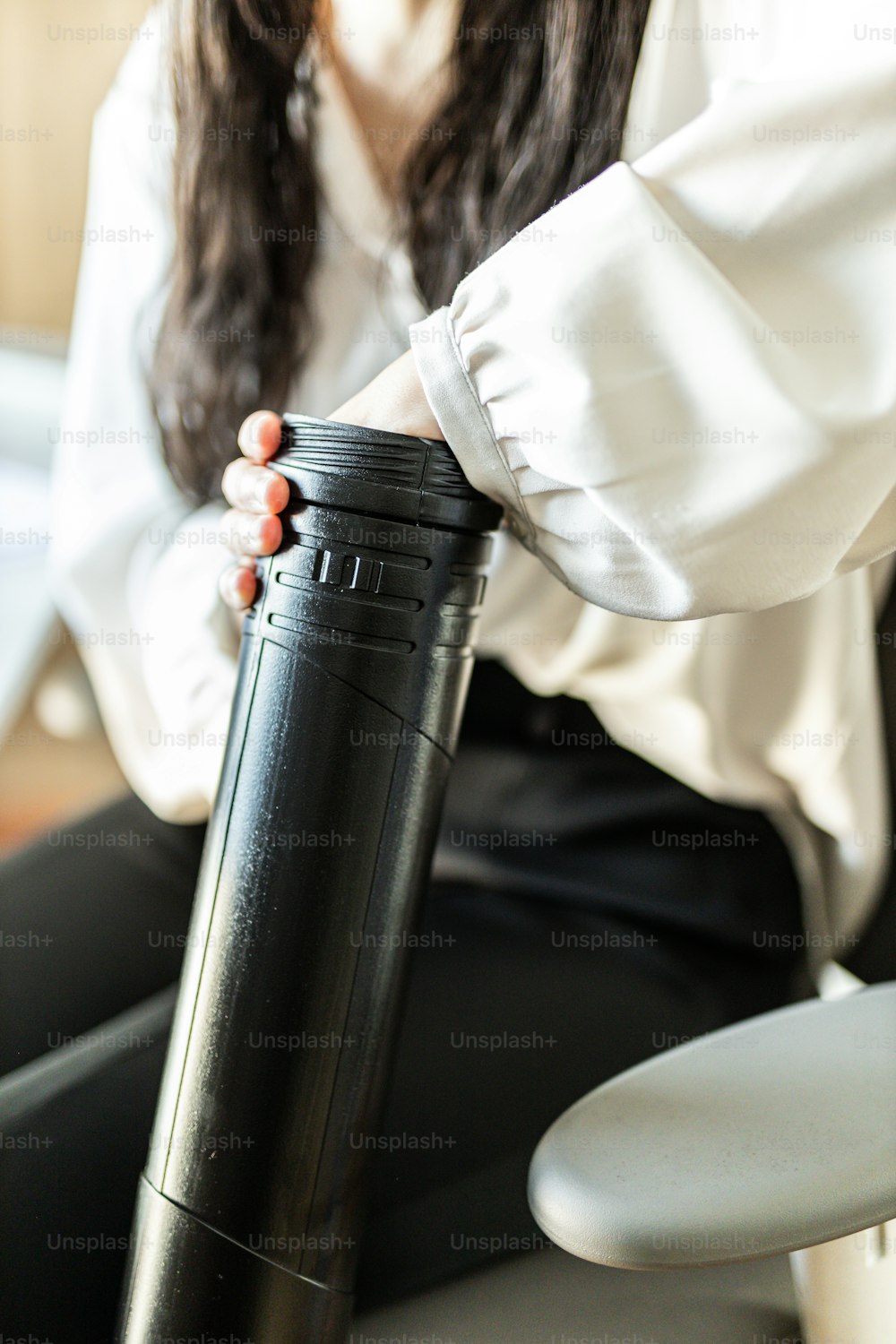 a woman sitting on a chair holding a black cup