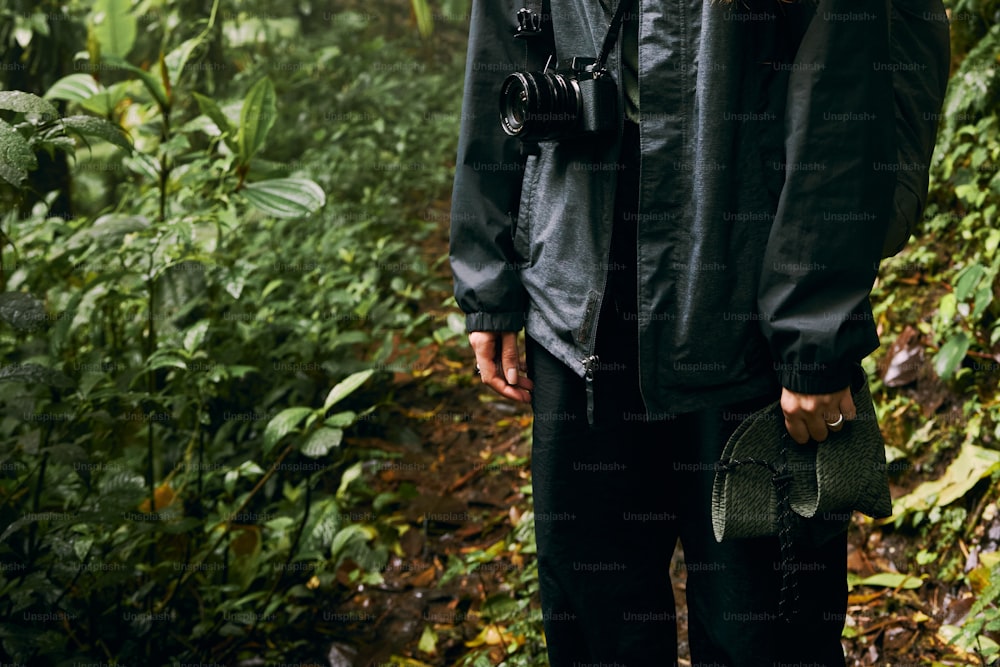 um homem em pé em uma floresta segurando uma câmera