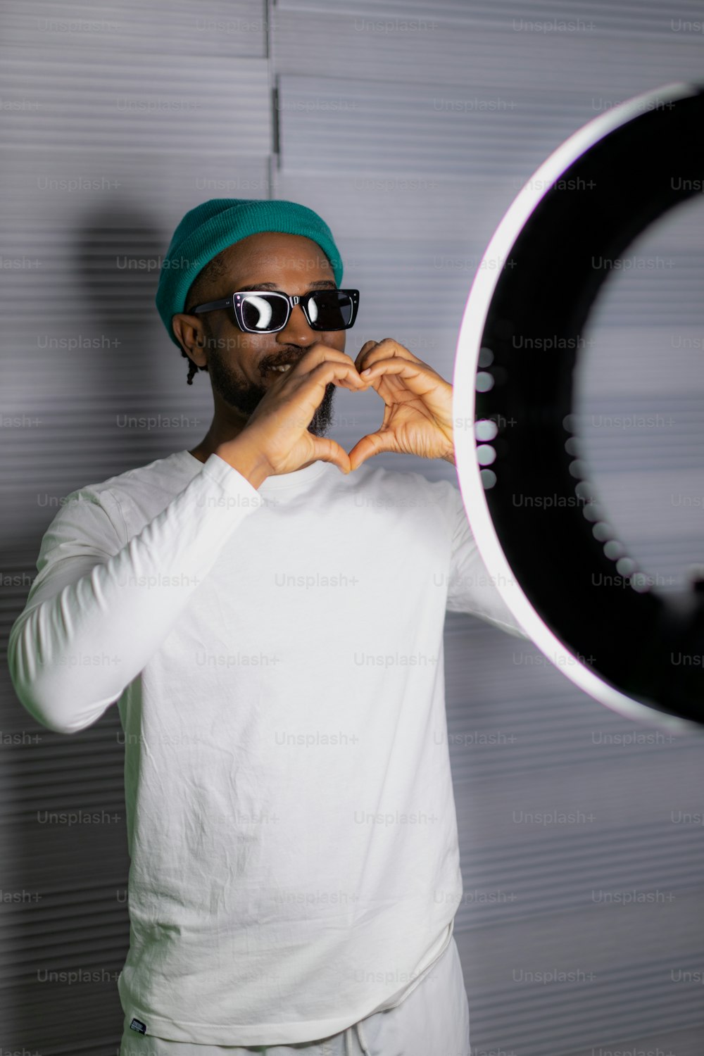 um homem usando óculos escuros e um turbante fazendo uma forma de coração com as mãos