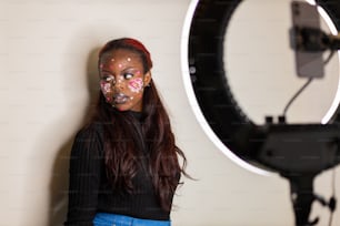 Una mujer con pintura facial parada frente a una cámara
