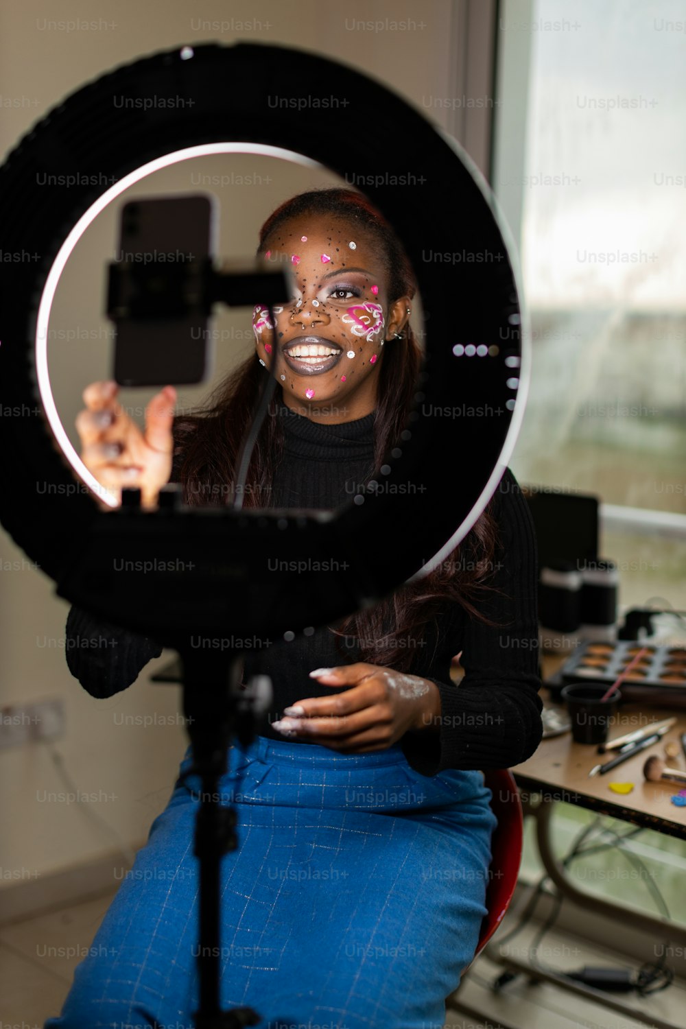 a woman sitting in front of a camera with her face painted