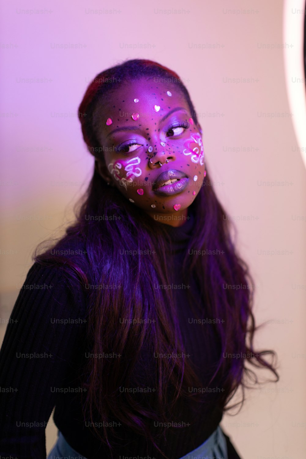 Une femme avec un maquillage violet et des lumières roses sur le visage