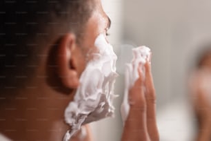 a man shaving his face in front of a mirror