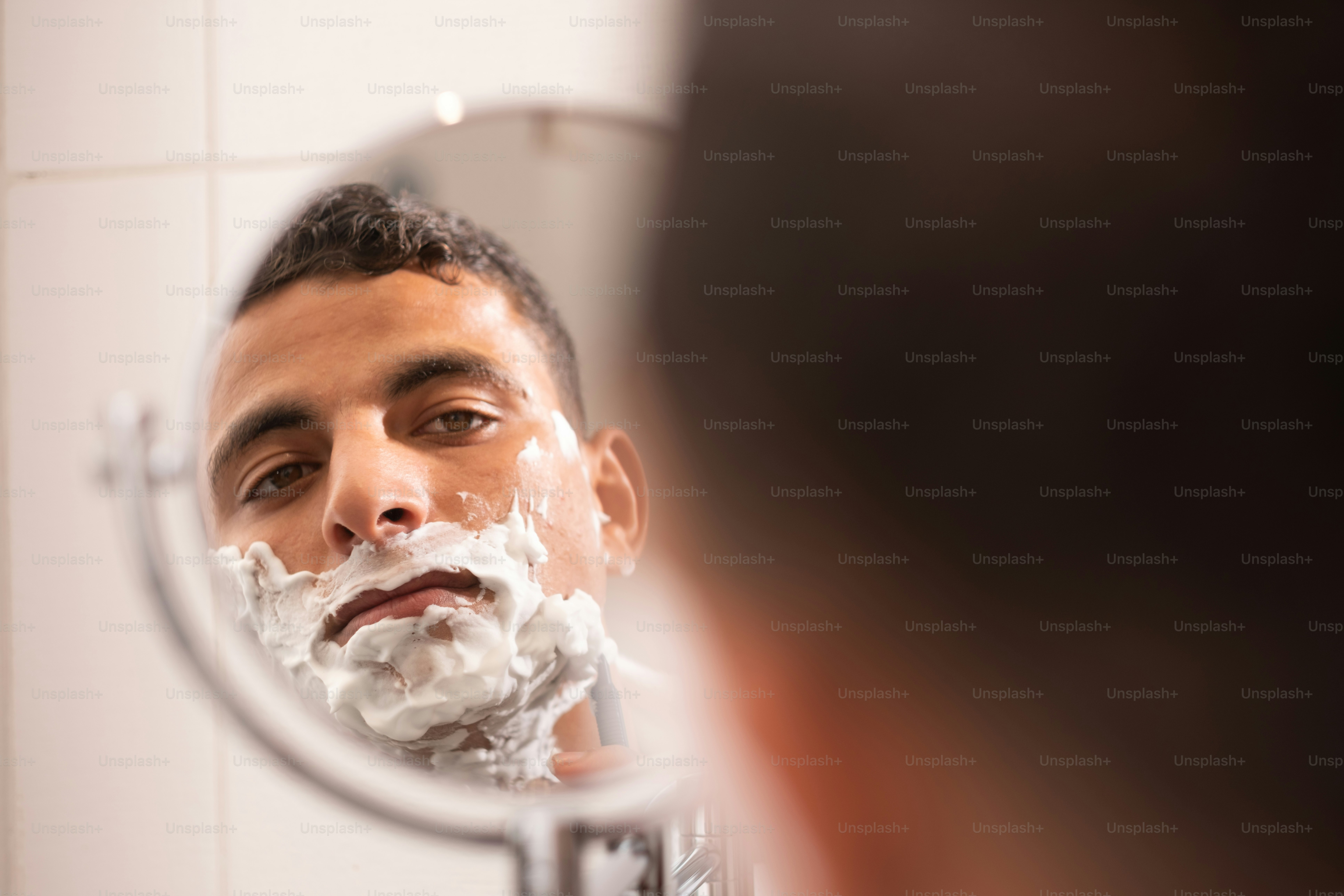 a man shaving his face in front of a mirror