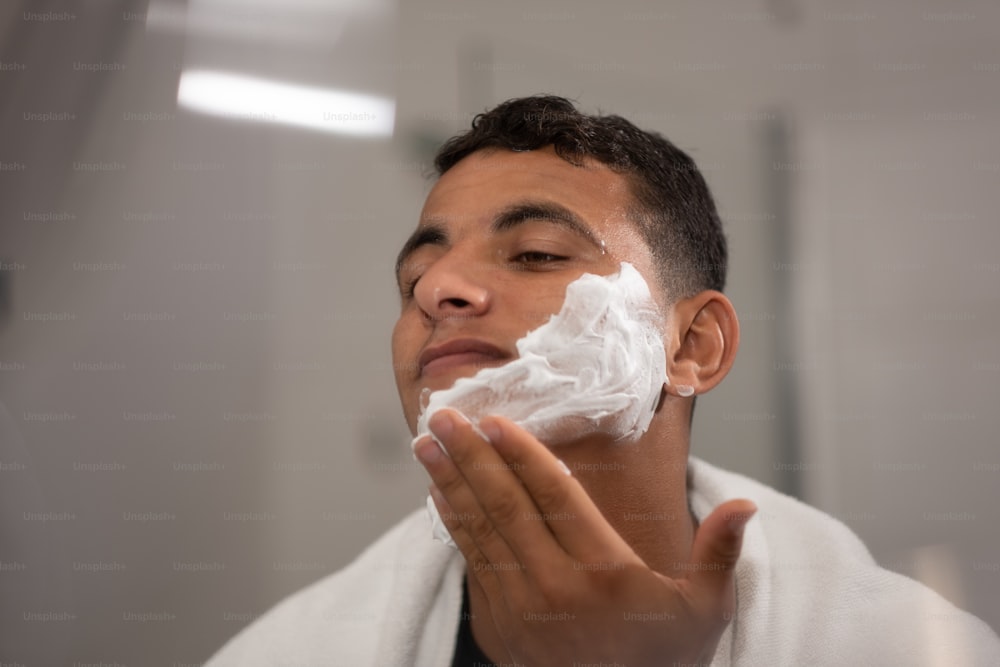 a man shaving his face in a bathroom
