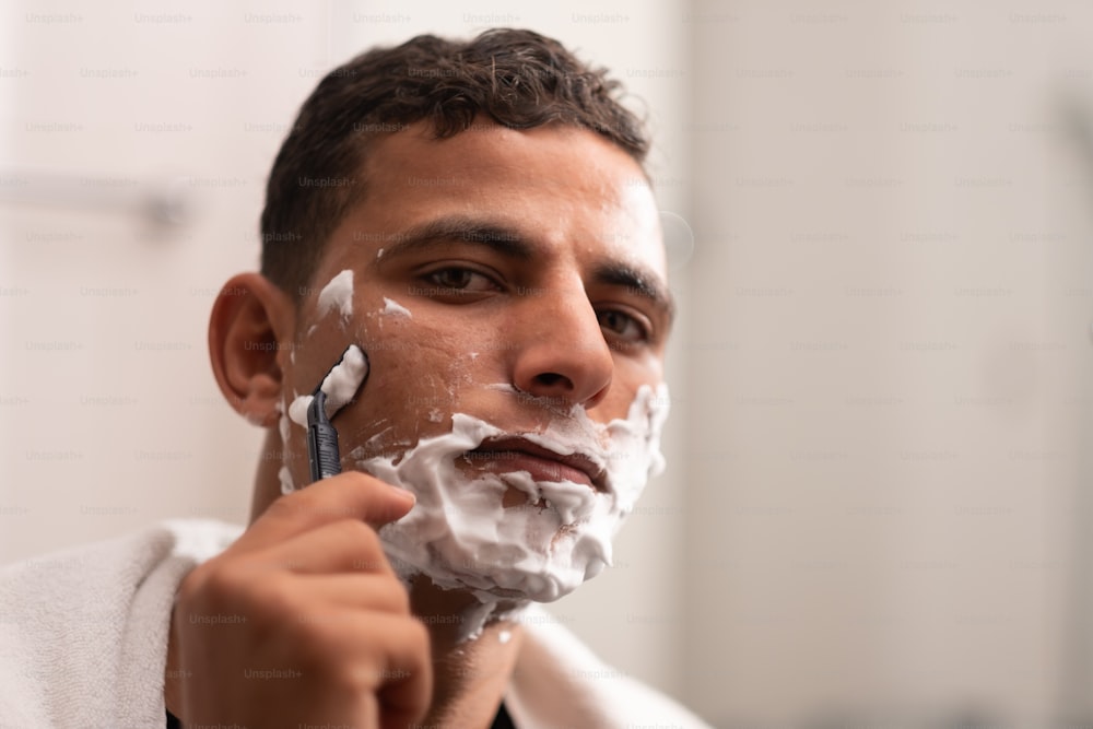 Un hombre afeitándose la cara con una navaja de afeitar