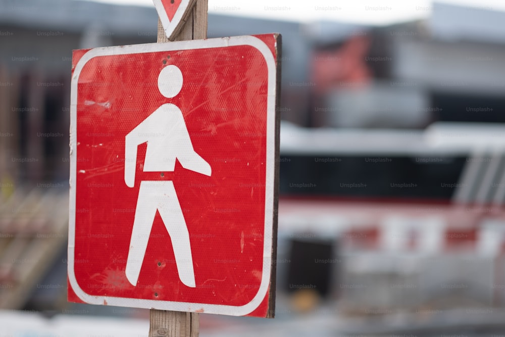 a red and white pedestrian sign on a wooden pole