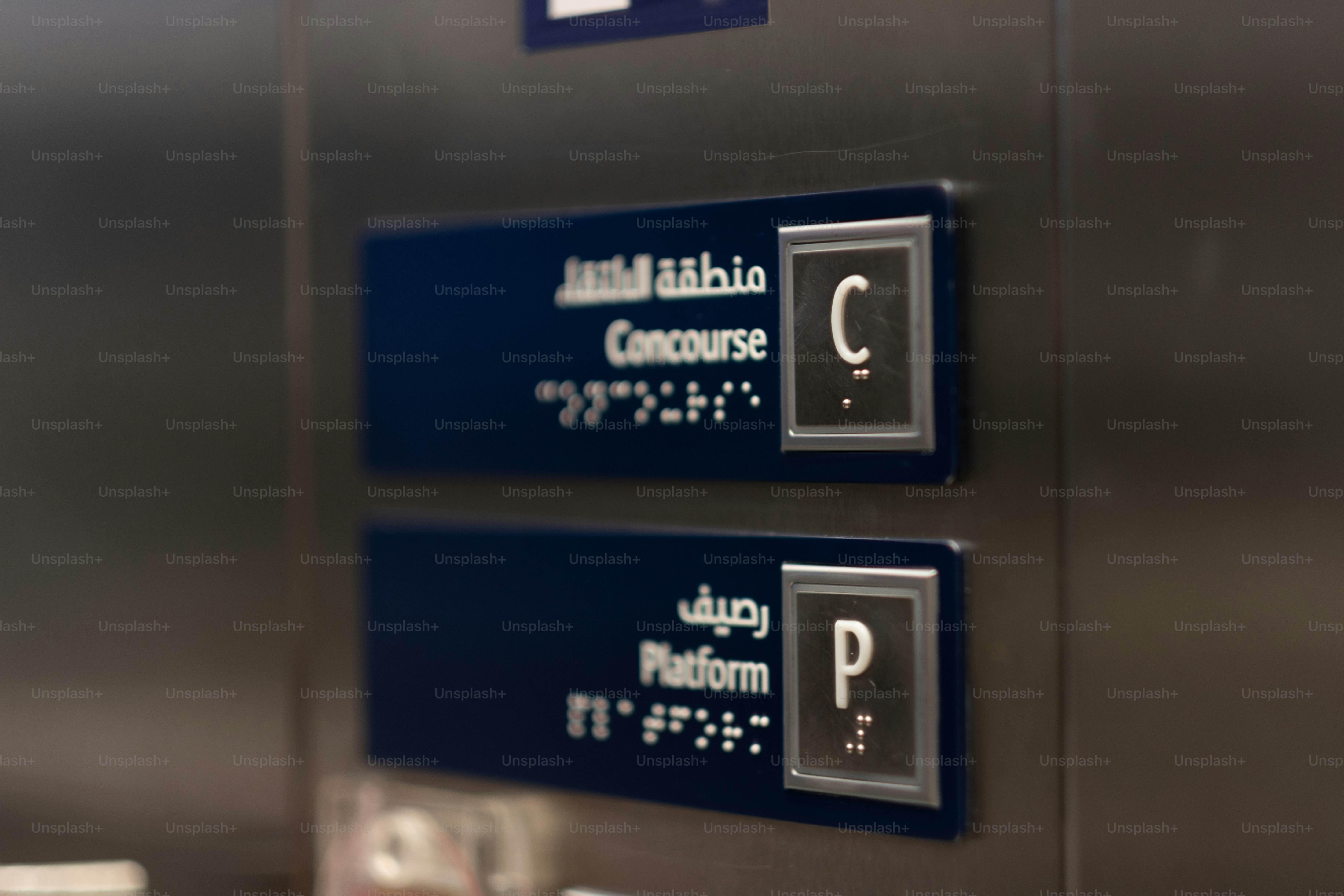 Elevator buttons in English, Arabic, and braille for the concourse and platform of a train station.