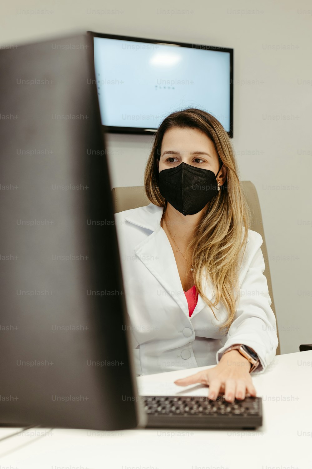a woman in a white lab coat wearing a black face mask