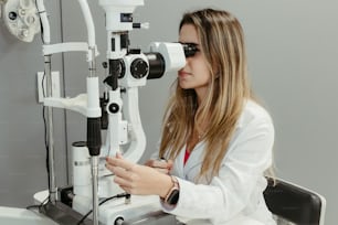 a woman in a white lab coat looking through a microscope