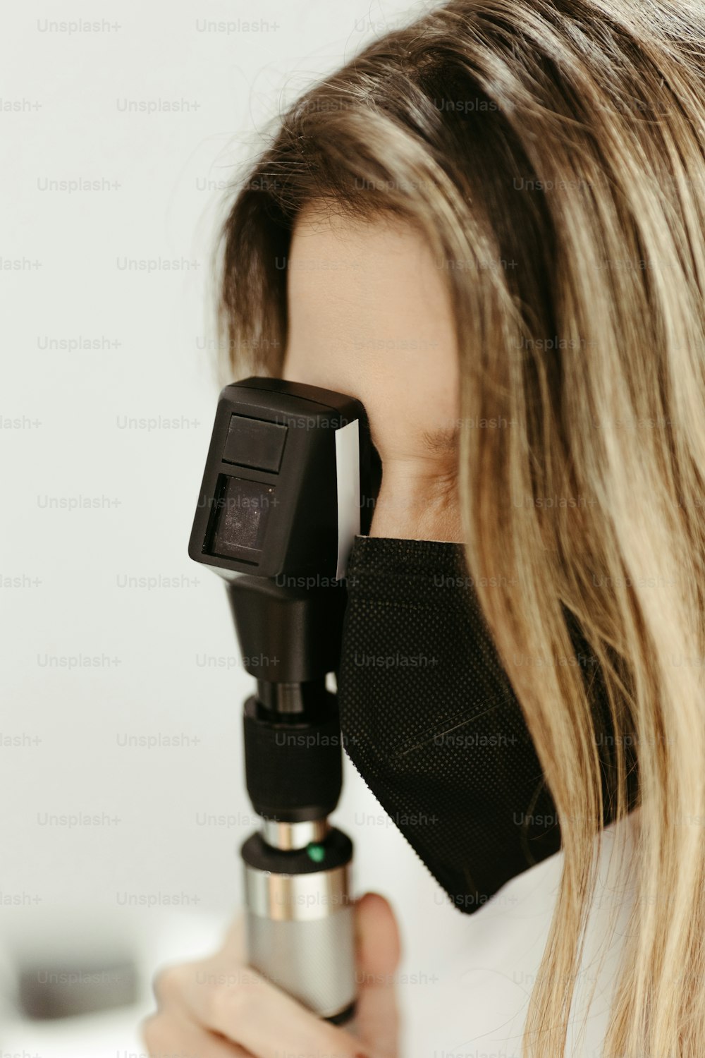 uma mulher usando uma máscara facial olhando através de um microscópio