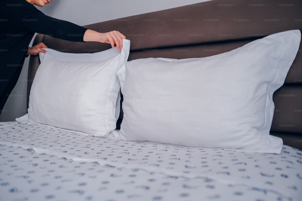 a woman putting a pillow on top of a bed