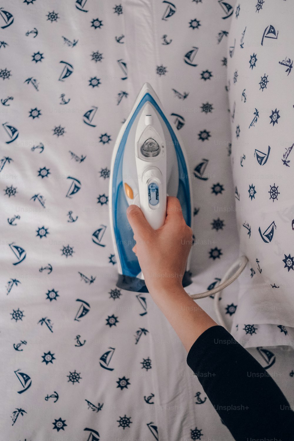 a person ironing a sheet with a blue and white iron