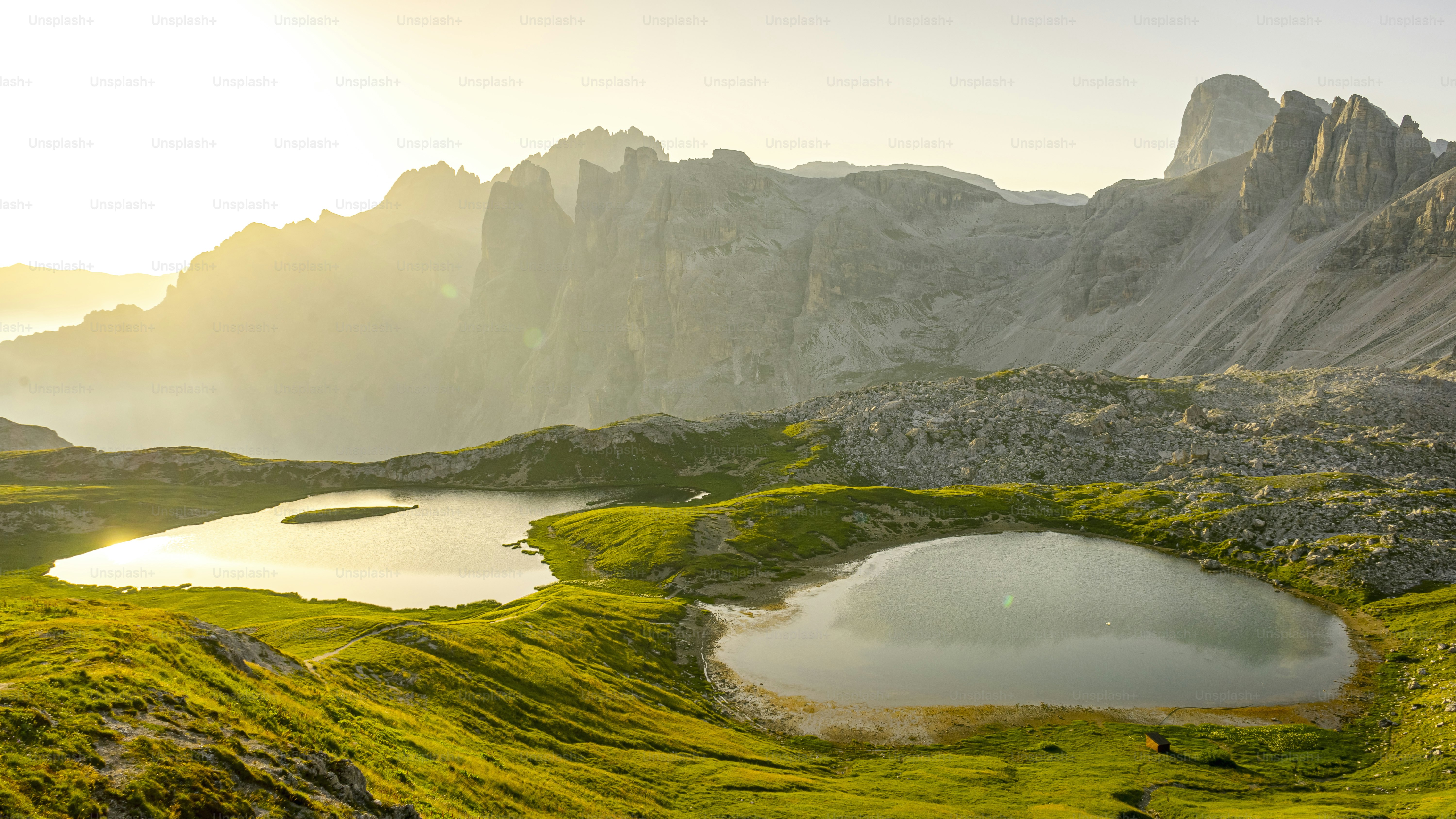 a mountain range with a lake surrounded by green grass