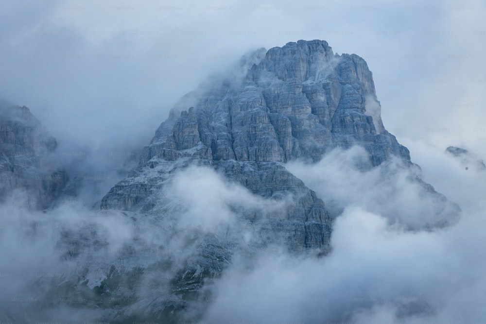 a very tall mountain surrounded by clouds in the sky