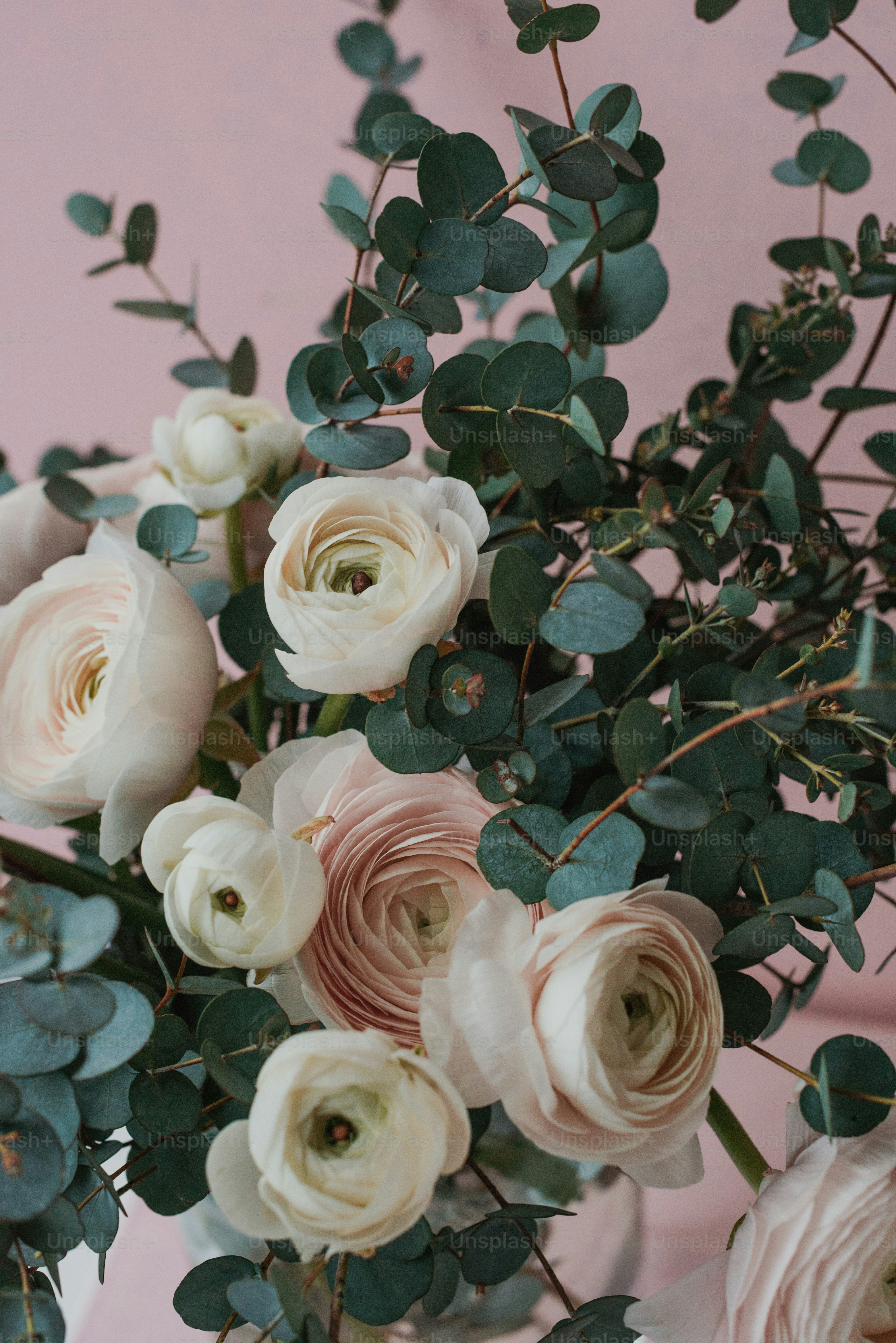 Un vase rempli de nombreuses fleurs blanches et roses