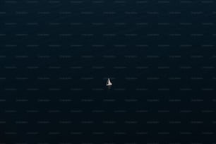 a lone sailboat in the middle of the ocean