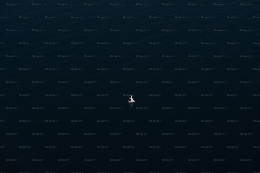 a lone sailboat in the middle of the ocean