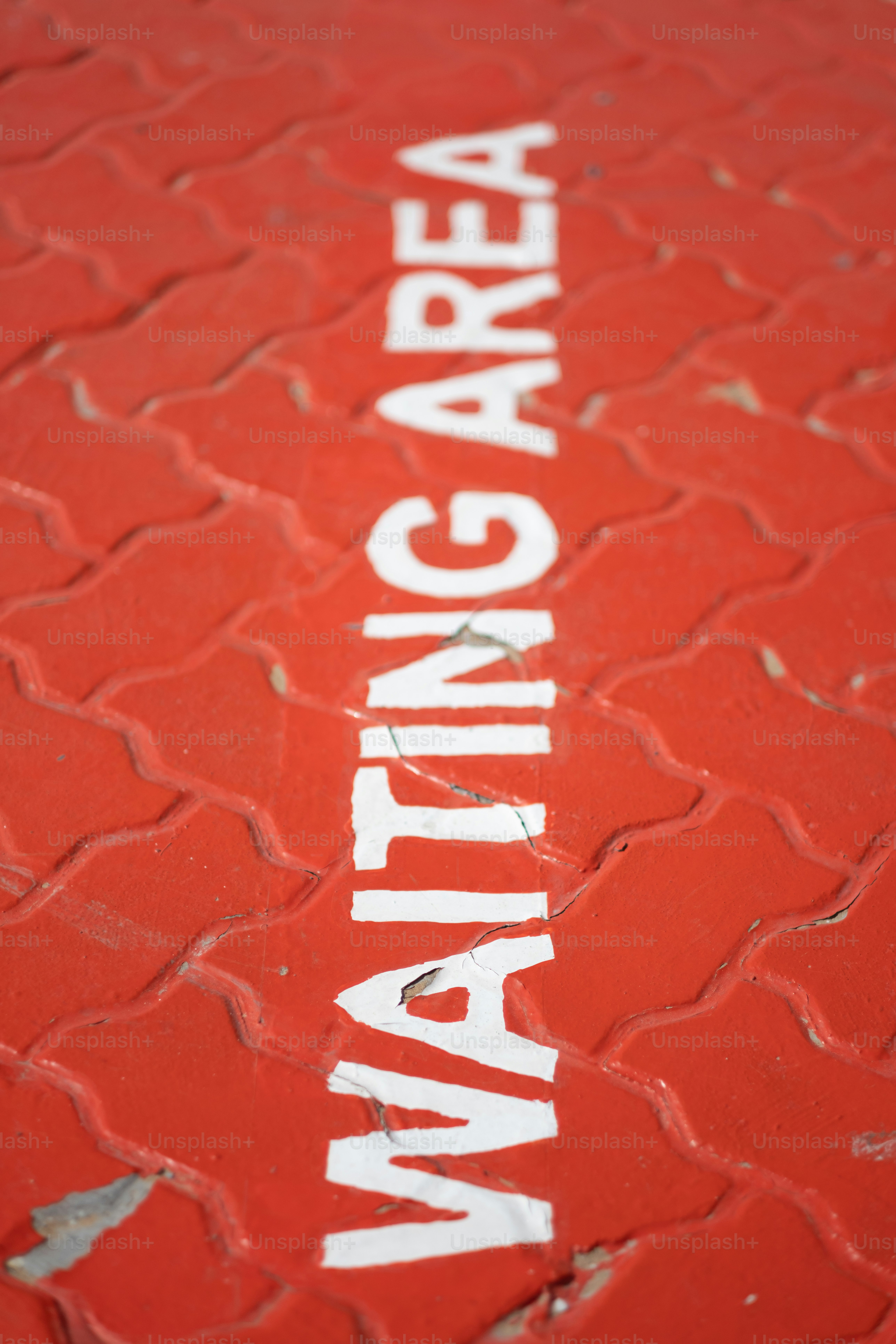 A red 'waiting area' sign on the ground at a busy intersection.