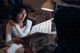 a woman sitting in a chair looking at a color chart