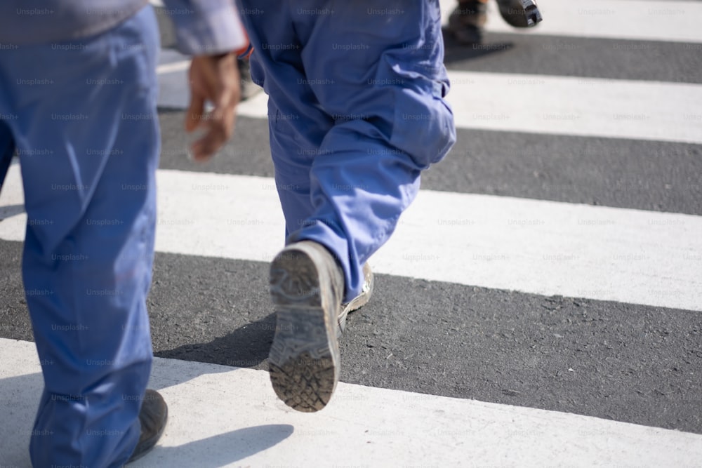 um homem andando através de uma faixa de pedestres segurando um telefone celular