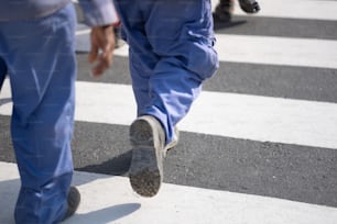 a man walking across a cross walk holding a cell phone