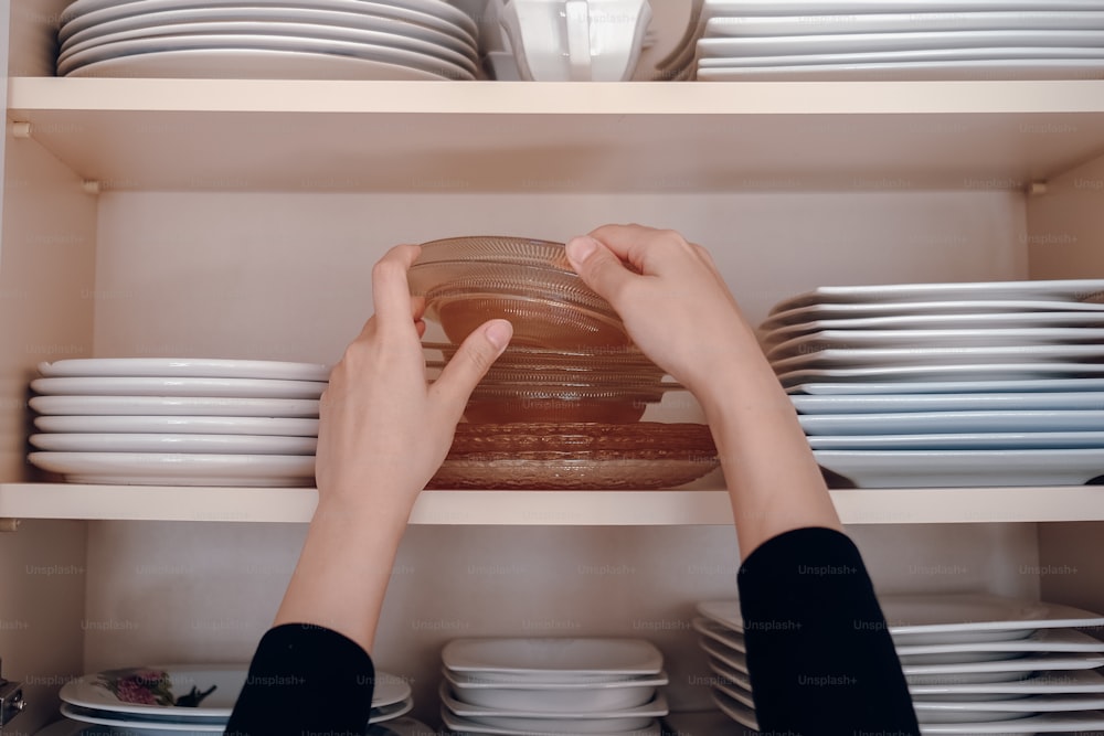 a person reaching for a plate on a shelf
